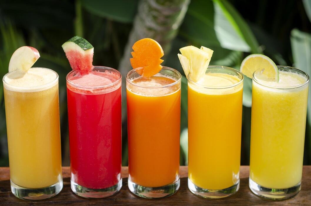 mixed fresh organic fruit juice glasses selection on sunny garden table photo
